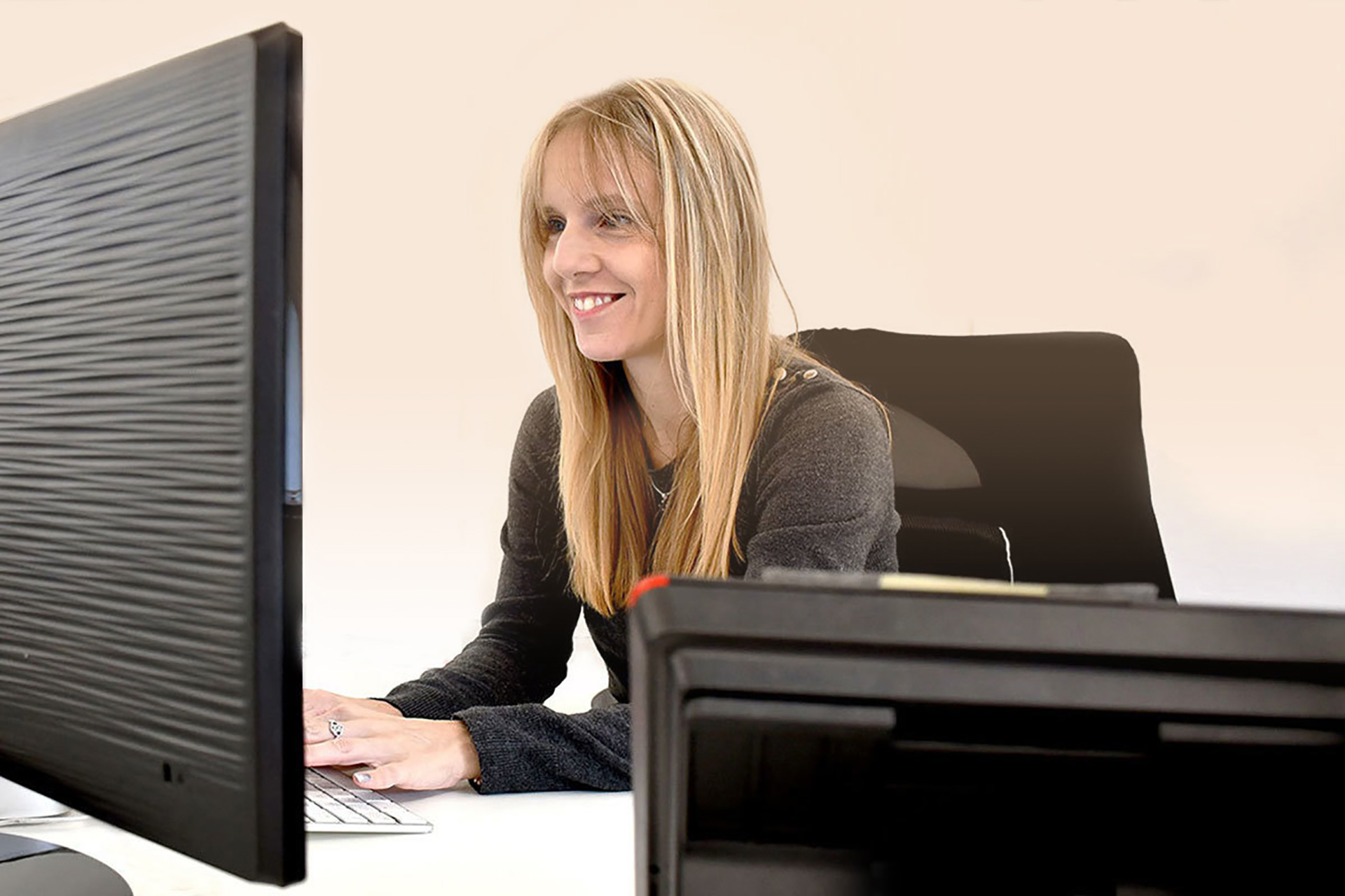 A smiling woman working on her desktop computer