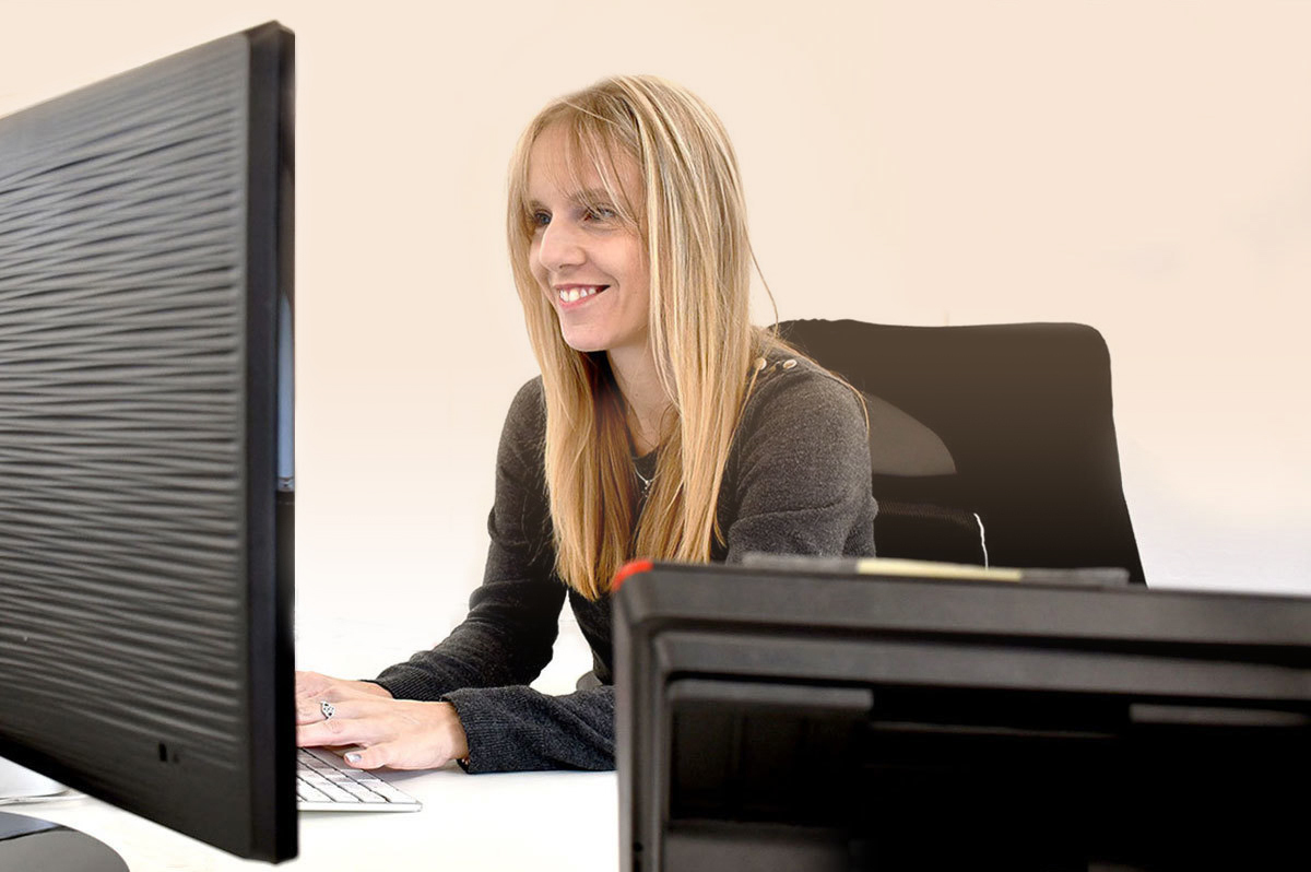 A smiling woman working on her desktop computer
