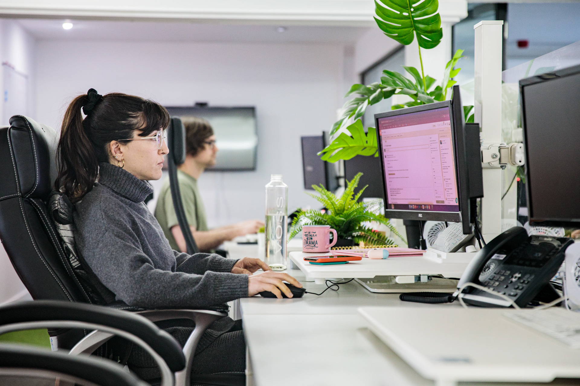 A female staff member sat at her desk working on her desktop computer